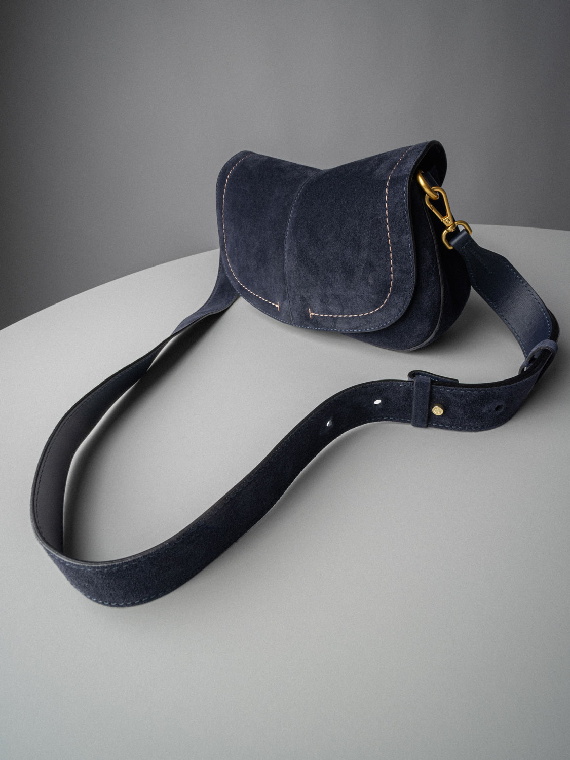 Καστόρινη χιαστί τσάντα saddle σε σκούρο μπλε με χρυσές λεπτομέρειες και φαρδύ λουρί
